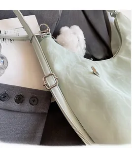 Detail of mint green backpack with adjustable strap and textured fabric with pom-pom