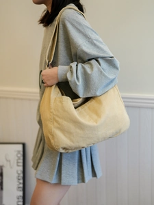 Detail of light yellow canvas crossbody bag with front pocket and soft washed texture