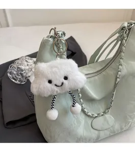 Detail of soft white cloud plush charm with striped cords attached to mint green handbag