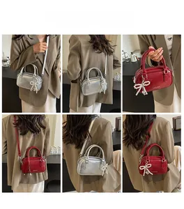 Detailed view of women's metallic silver Boston bag featuring a pearl bow pendant