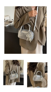 Detail view of silver shiny mini Boston bag with pearl bow pendant and metal texture
