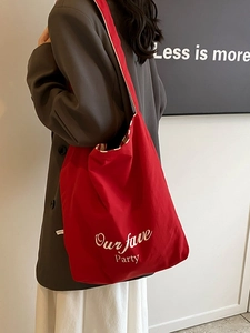 Minimalist red canvas tote bag with Our fave Party print worn on a female shoulder