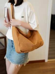 Macro shot of large-capacity caramel canvas messenger bag showing texture and drape