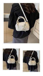Close-up of cream oil wax leather Boston bag with pearl bow and heart charm detail