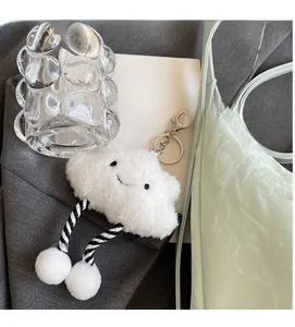 Close-up of fluffy white cloud plush charm with striped rope legs on a stylish handbag