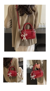 Detail of red wax leather Boston bag with pearl bow charm and silver heart pendant