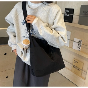 Detailed view of the large black nylon tote bag with heart charm and wide shoulder strap