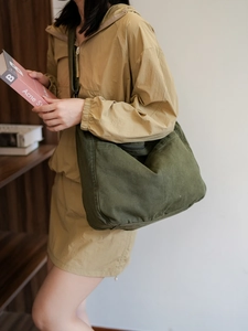 Detail view of military green nylon messenger bag showing spacious side pocket and canvas texture
