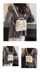 Detail des cremefarbenen Mini-Rucksacks mit Sternschnalle und Plüschtier-Anhänger