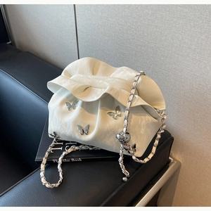 Détail du sac nuage blanc plissé avec breloque papillon argentée et bandoulière