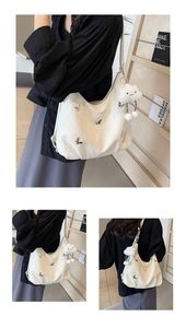 Detailed view of white hobo tote bag with metal butterfly and plush cloud charm