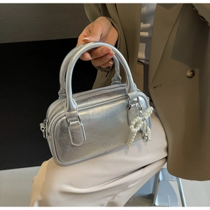Detail of silver cracked leather handbag with pearl bow charm and embossed logo