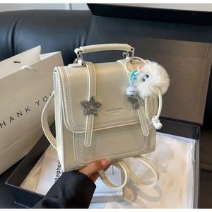 Detailansicht des Mini-Rucksacks in Creme mit Sternen und Plüsch-Anhänger