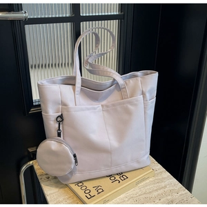 Makroaufnahme einer lila Nylon-Tragetasche mit Seitentasche und passendem Rundbeutel-Charm