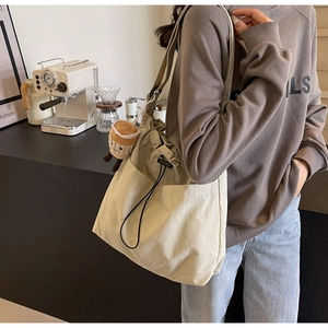 Close-up of beige nylon drawstring tote bag featuring side pockets and a plush coffee charm