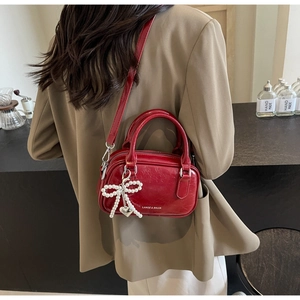 Close-up of wine red oil wax leather handbag featuring a pearl bow and heart charm