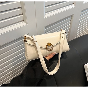 Detail of creamy white faux leather baguette bag with a vintage bronze metal clasp