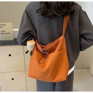 Detail of orange nylon tote bag with drawstring closure and cute coffee cup plush charm