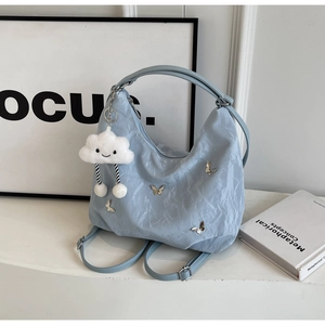 Detail of light blue textured tote bag with silver butterflies and cloud plush charm