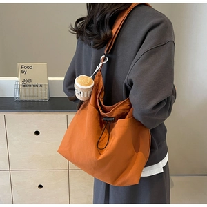 Detail view of the orange nylon tote bag side drawstring and cute coffee cup plush charm