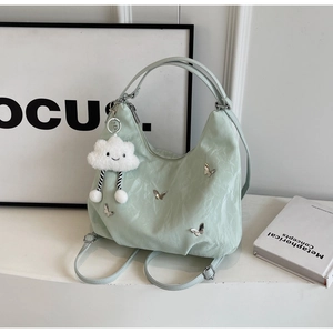 Detail of light green crossbody bag with silver butterflies and cloud charm
