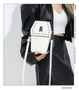 Gothic white coffin bag with skull logo and metal studs worn by model in biker outfit