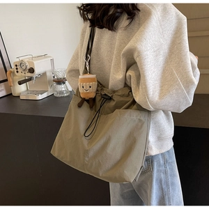 Olive green nylon tote bag with drawstring closure and cute coffee cup plush charm detail