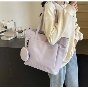 Detail der fliederfarbenen Nylon-Tote mit Fronttaschen und rundem Münzfach-Anhänger