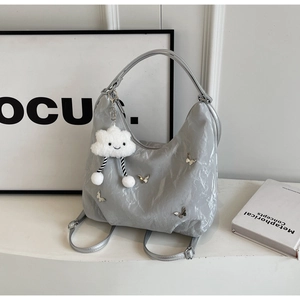 Detail of silver tote bag with metal butterfly accents and plush cloud charm