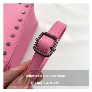 Detailed close-up of pink crossbody bag with metal studs and adjustable shoulder strap