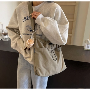 Detail of khaki nylon tote bag with drawstring closure and cute coffee cup plush charm