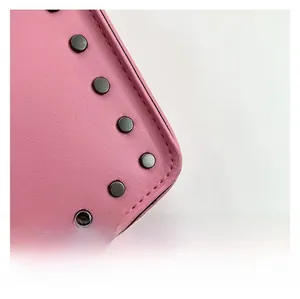 Detail shot of pink leather crossbody bag featuring black metal rivets and fine stitching