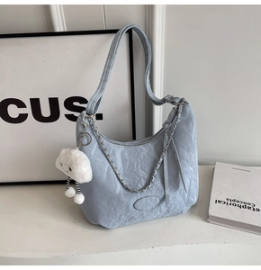 Detail of light blue pleated shoulder bag with silver chain and white plush cloud charm
