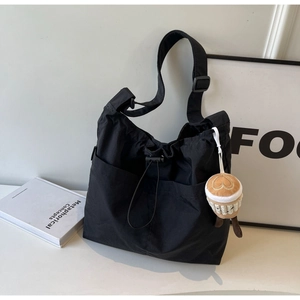 Detail of black nylon tote bag with drawstring closure and cute plush coffee cup charm