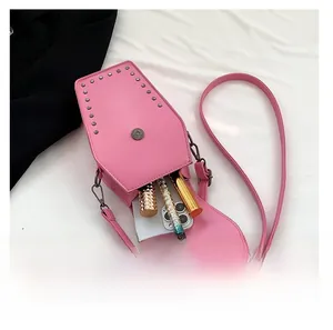 Pink coffin-shaped crossbody bag with rivets showing interior phone and makeup storage