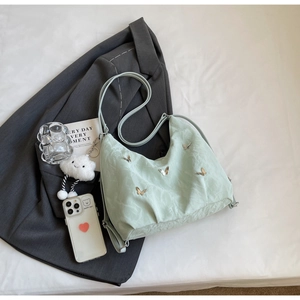 Detail of mint green pleated cloud bag with silver butterfly metal charms and long strap