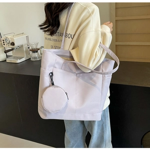 Detailansicht der helllila Nylon-Tragetasche mit Vordertaschen und einer runden Münztasche