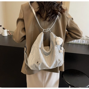 Silver hobo backpack with butterfly charms and bear pendant shown on model in cafe