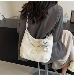 Detail of off-white leather tote with silver chain and cute cloud charm on grey blazer