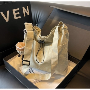 Detail of light beige pleated nylon tote bag with drawstring closure and coffee cup charm