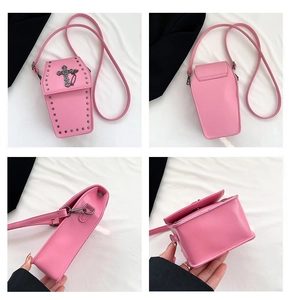 Detail view of pink coffin-shaped crossbody bag with metal cross and studded edge