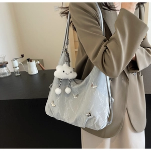 Silver pleated tote bag with butterfly charms and white plush pendant on female model