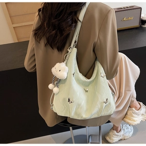 Light green hobo bag with silver butterfly charms and plush cloud pendant on shoulder