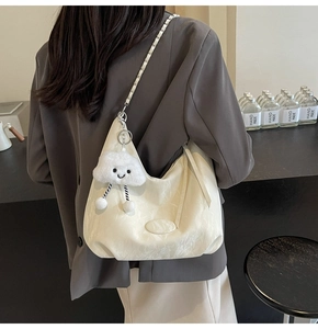 Detail of off-white pleated hobo bag with braided chain strap and cloud plush charm