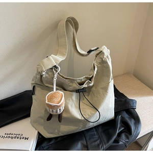 Detail of beige nylon tote bag with drawstring side and cute coffee plush charm accessory