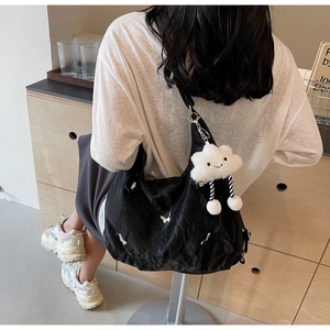 Detail view of black hobo bag with white butterfly print and plush cloud charm accessory
