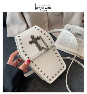 Detail of white coffin-shaped goth crossbody bag with rivets and cross pendant