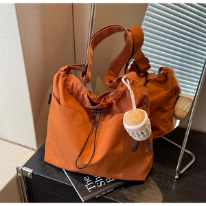 Detail of orange nylon tote bag with drawstring closure and cute plush coffee cup charm