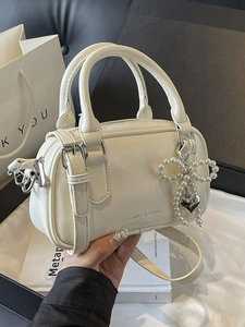 Creamy white mini Boston bag in oil wax leather with pearl bow and heart charm