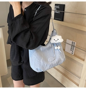 Detailed texture of light blue pleated shoulder bag with silver chain and cloud charm